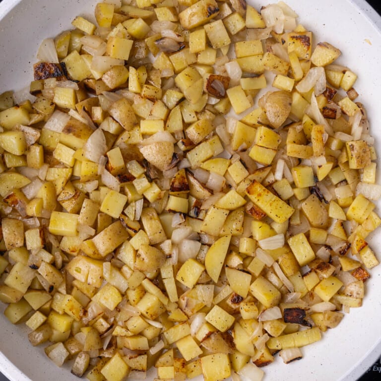 Potatoes and onions frying in a pan over high heat.