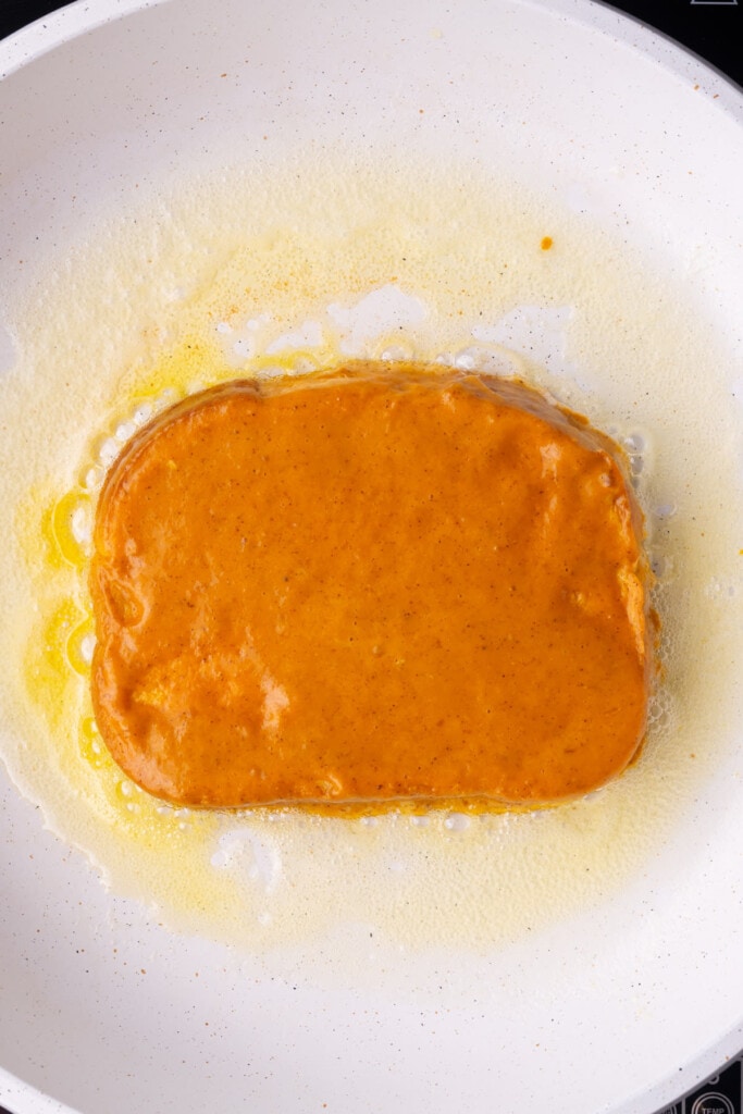 Adding pumpkin French toast to frying pan with butter.