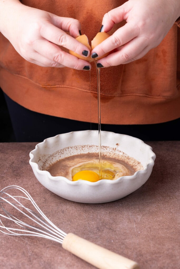 Cracking eggs into milk with pumpkin pie spice and brown sugar to make egg wash. 