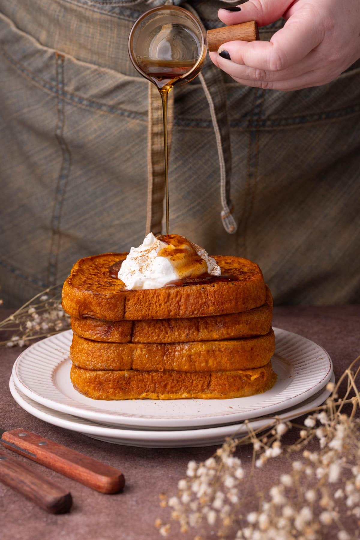 Pouring maple syrup onto French toast with pumpkin. 