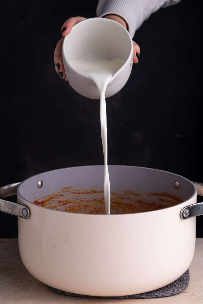 Adding cream to roasted garlic tomato soup. 