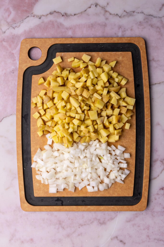 Diced potato and onion on a chopping board. 