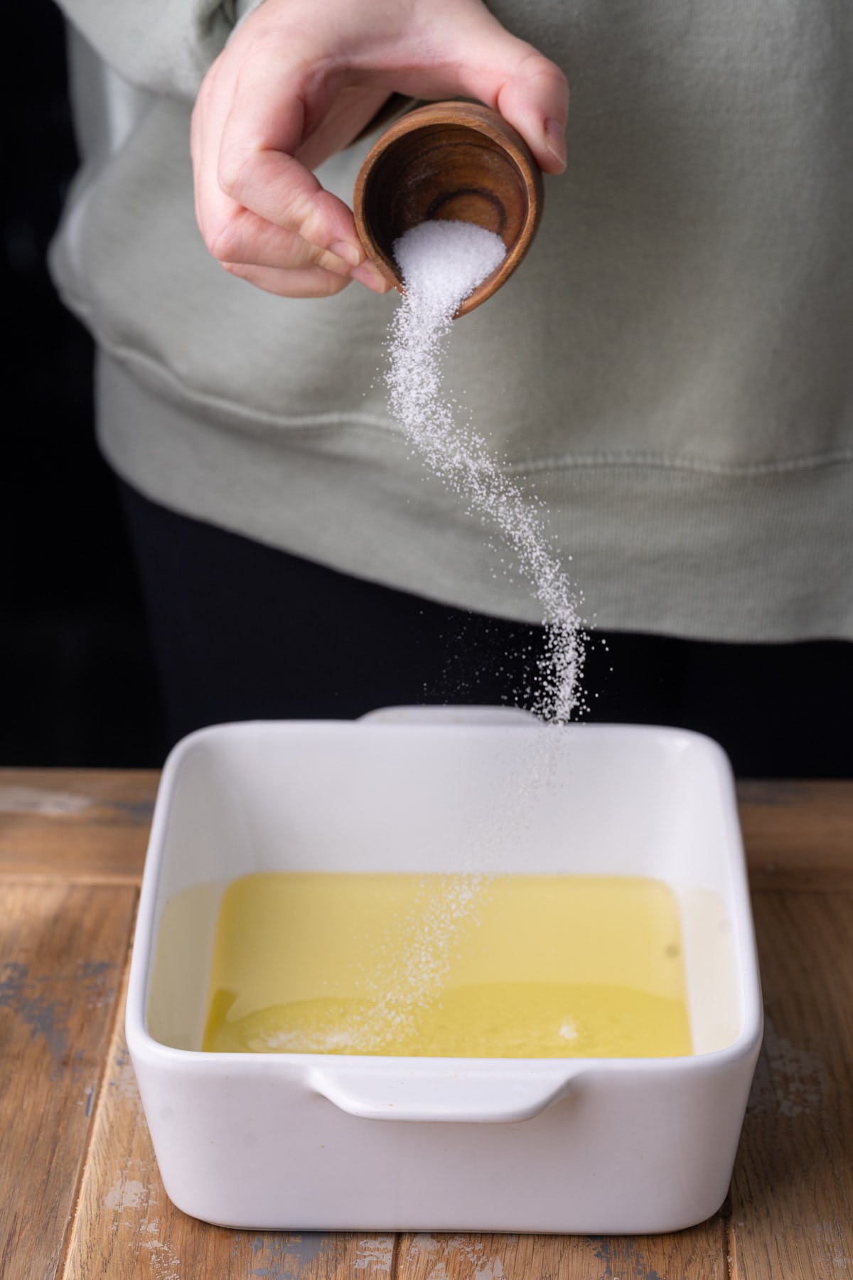 Adding salt to a baking dish with olive oil and honey. 