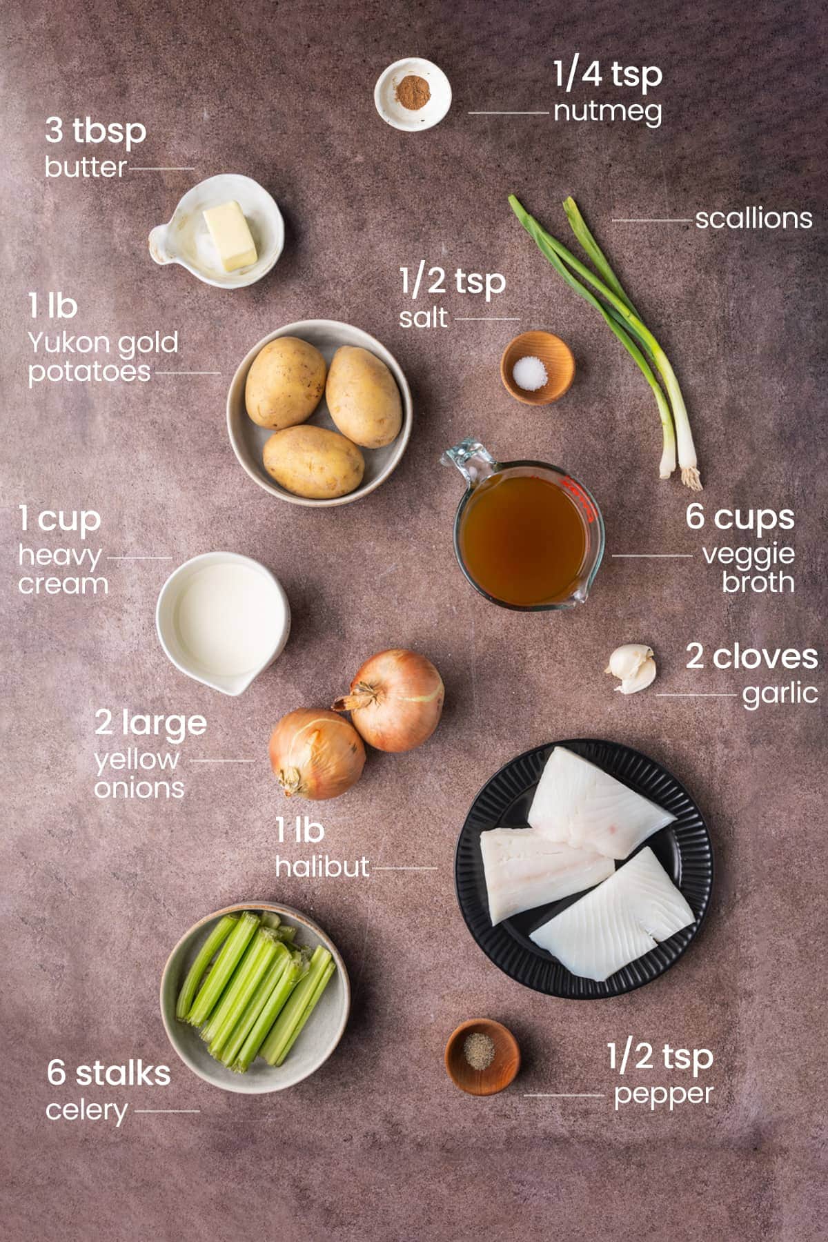 All ingredients needed for halibut chowder including nutmeg, butter, salt, scallions, yukon gold potatoes, vegetable broth, yellow onion, cream, garlic, halibut, pepper, and celery. 