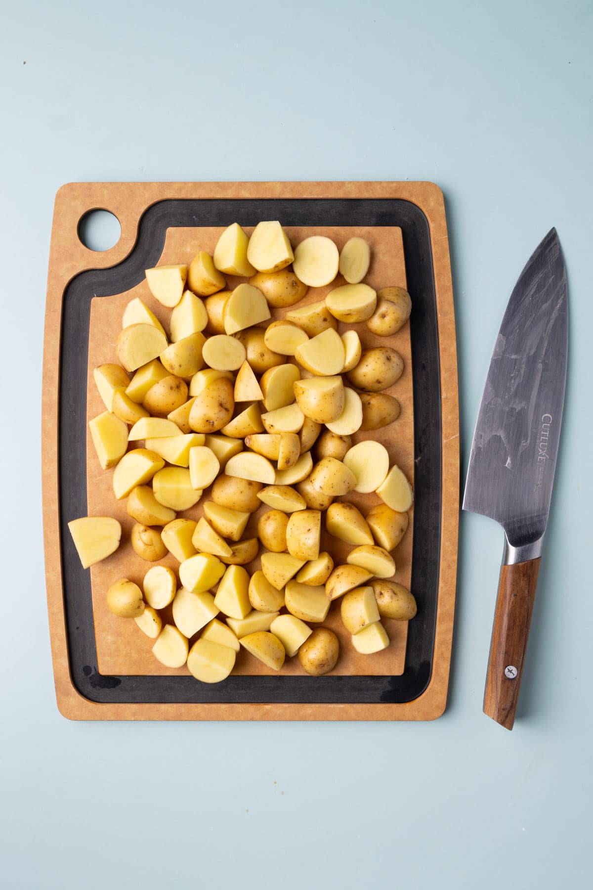 Honey gold potatoes on a chopping board cut into bite-sized wedges. 