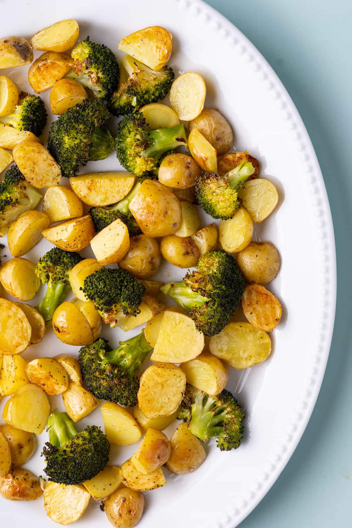 Close up of serving platter with roasted potatoes and broccoli. 