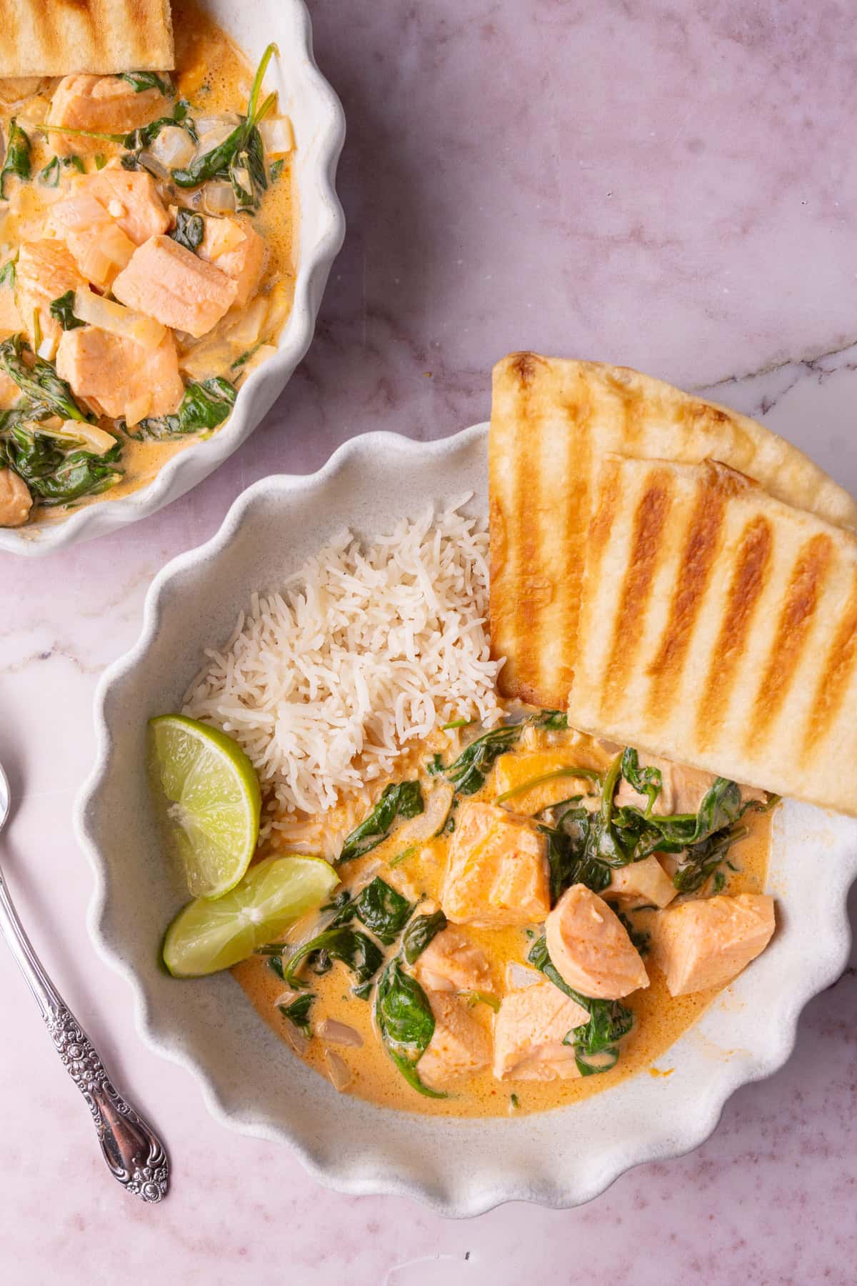 Close up of bowl with rice, salmon coconut curry, and grilled naan.