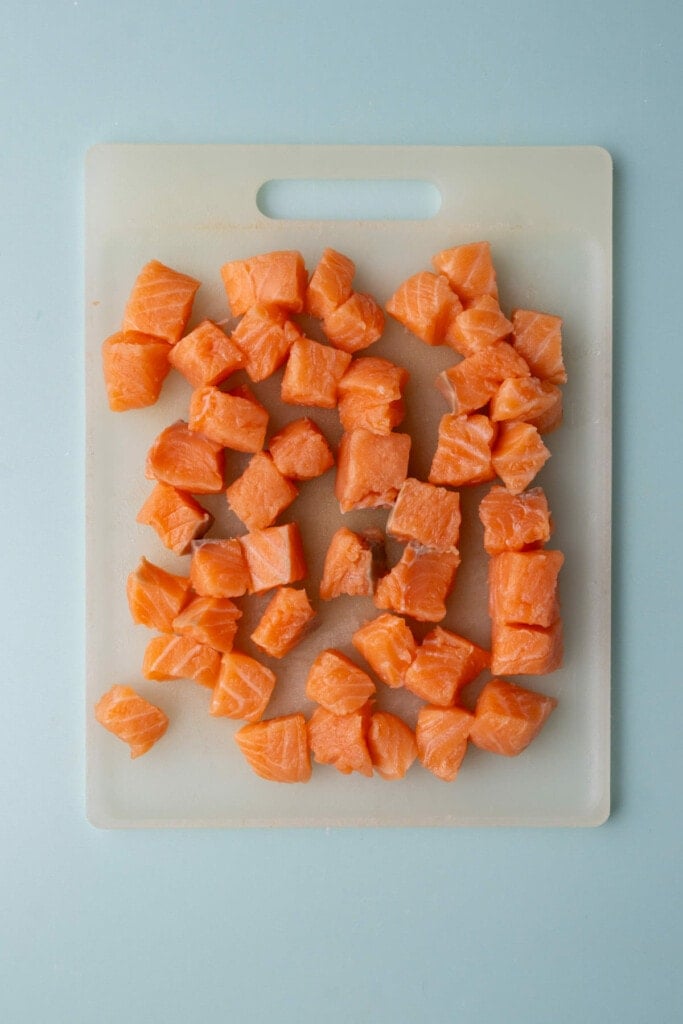 Cutting salmon into bite-sized cubes to poach in teriyaki sauce. 