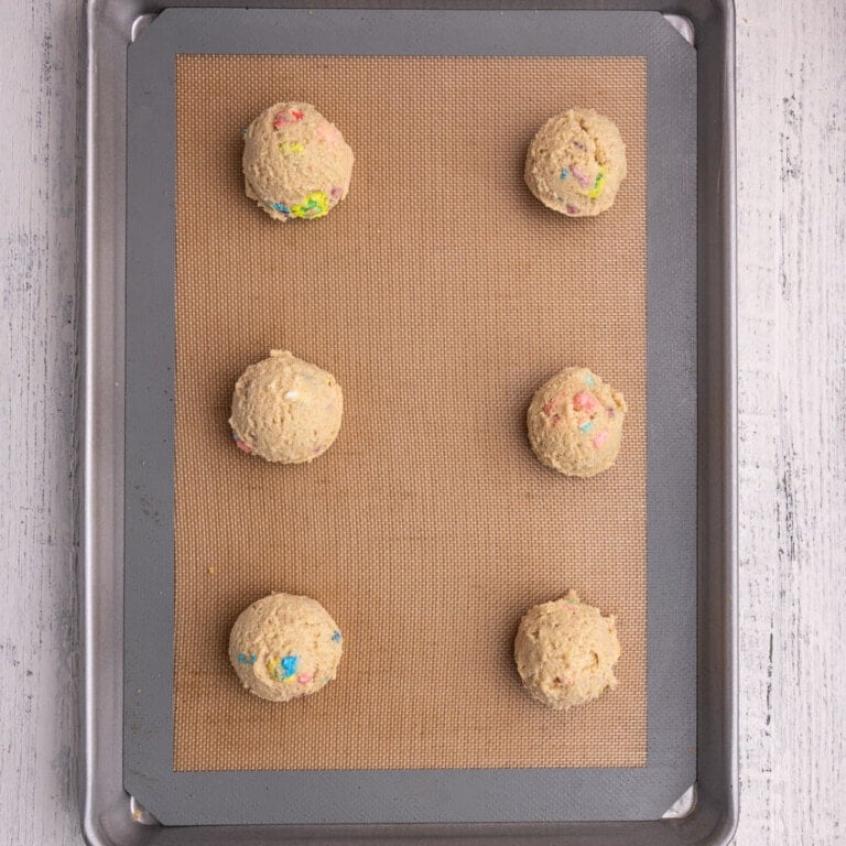 6 shaped Lucky Charms cookie dough balls ready to bake.