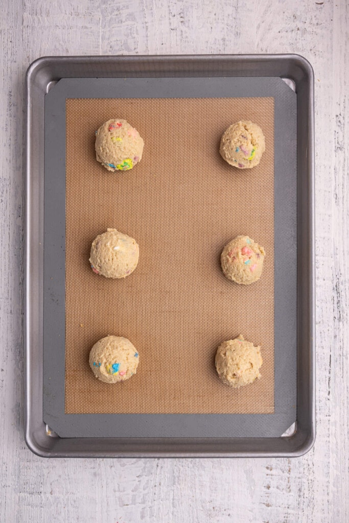 Lucky Charms cookie dough lined up on a baking sheet.