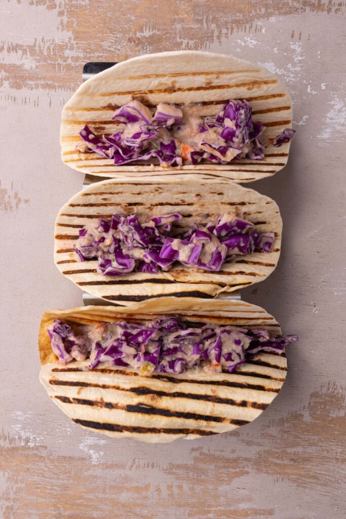 Assembling fish tacos with sweet and spicy cabbage.