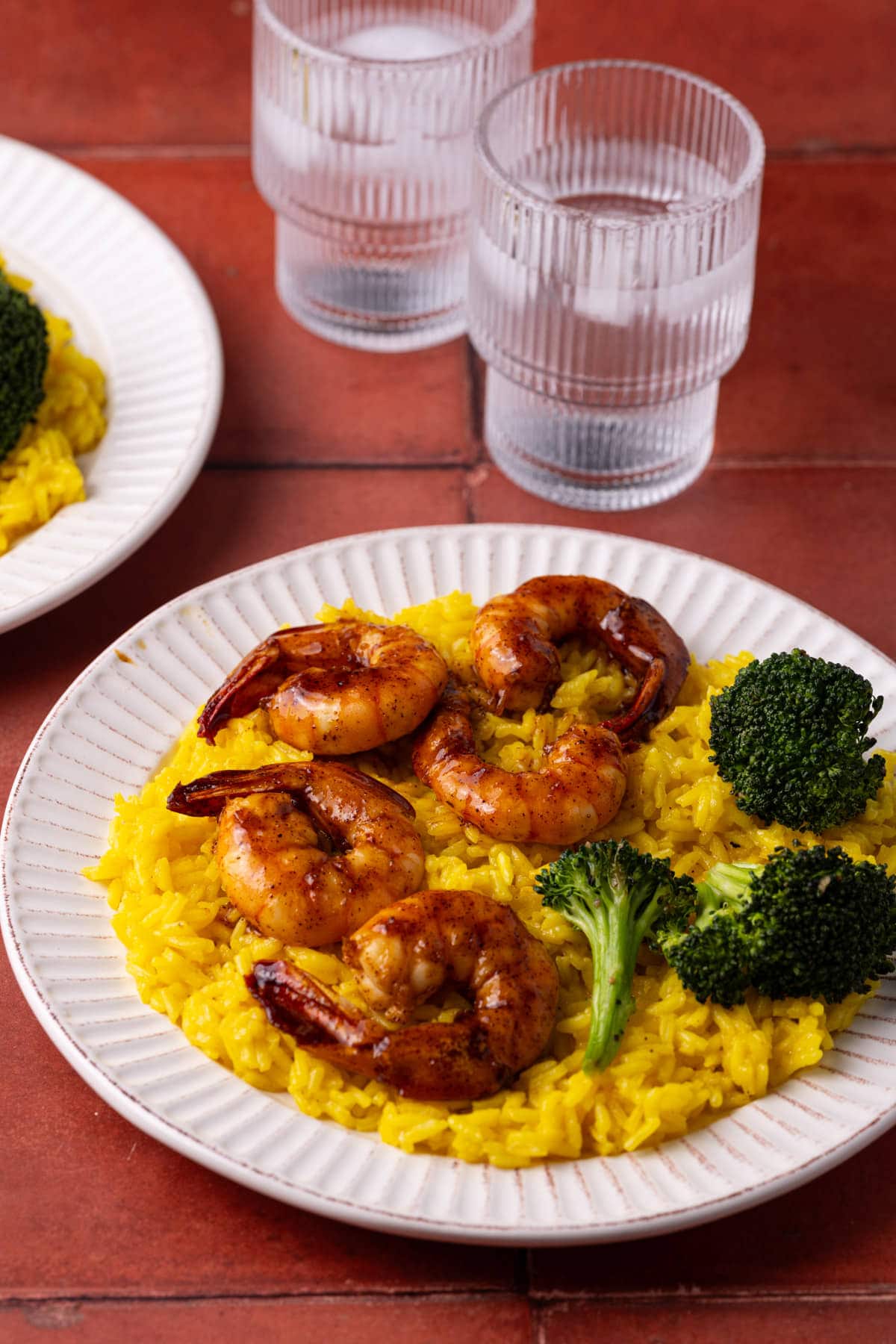Close up of tequila lime shrimp plated on top of rice and served with roasted broccoli.