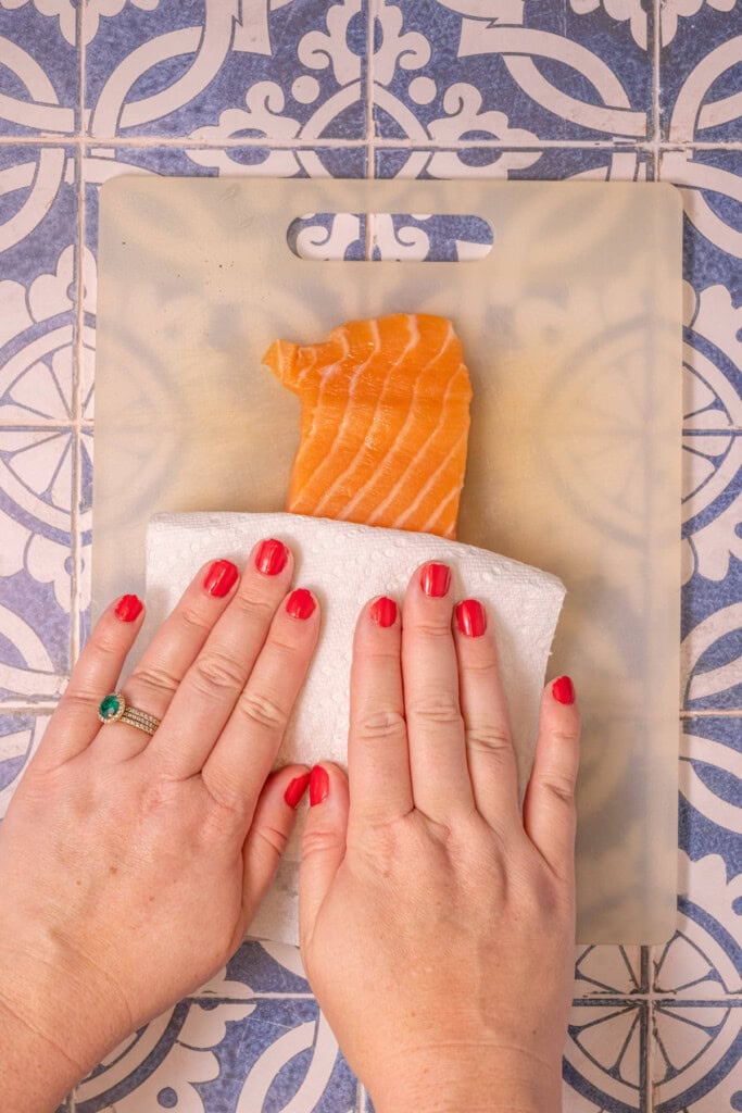 Patting salmon dry with a paper towel to reduce excess moisture and get the best texture when breaded and baked.