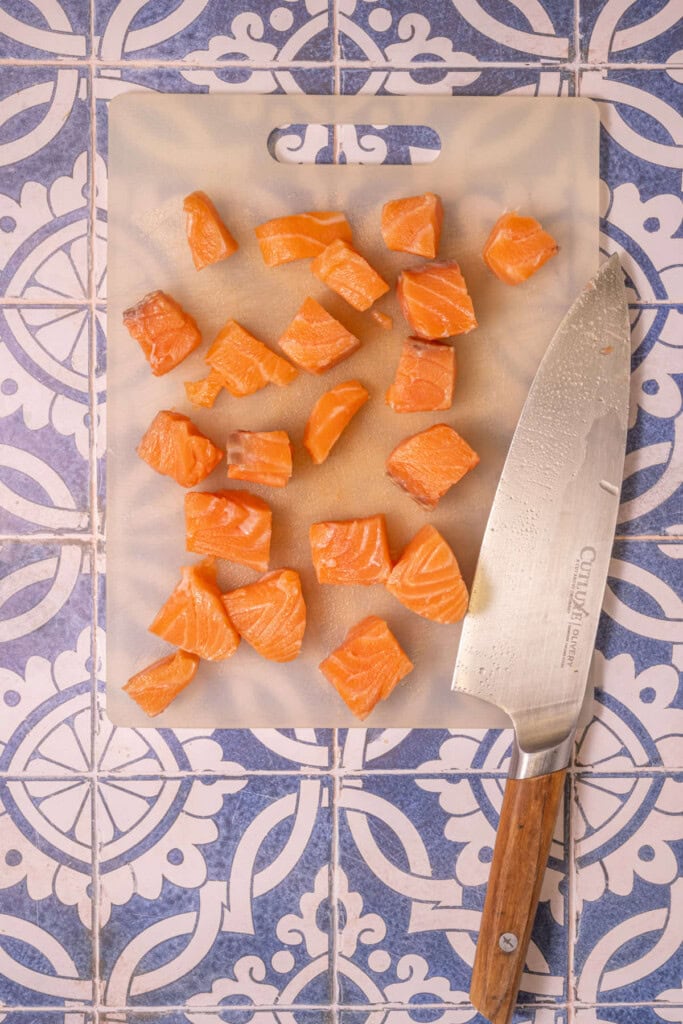 Slicing skinless salmon into little bite-sized cubes.