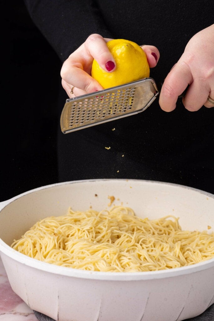 Zesting a lemon over a pan of pasta. 