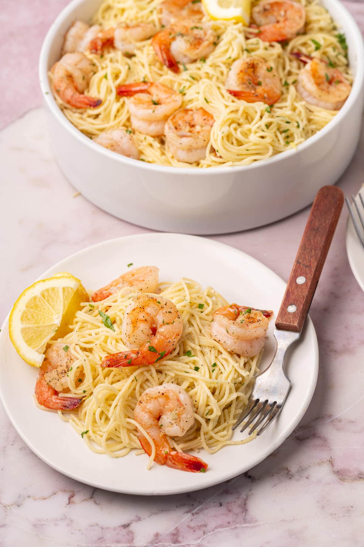 Lemon shrimp pasta served on a plate with a fork, with the serving bowl in the background. 