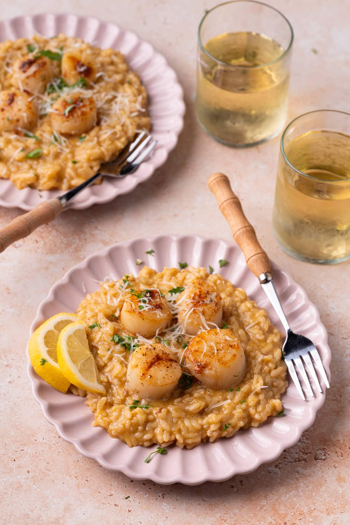Lemon risotto with seared sea scallops on a pink plate. 