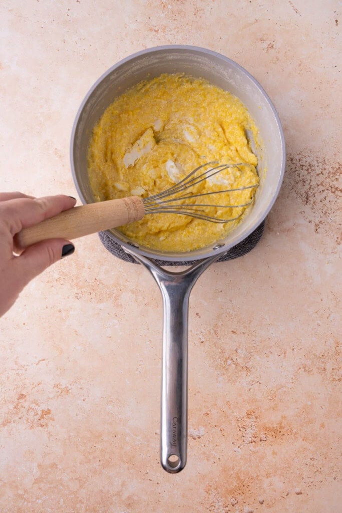 Whisking goat cheese into creamy cooked polenta. 