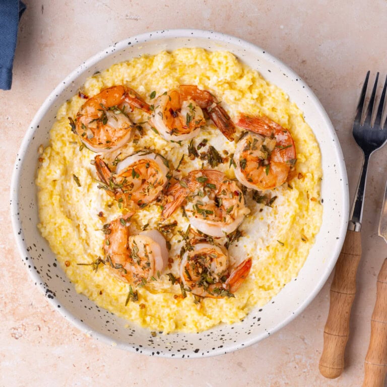 Herbed shrimp and polenta with goat cheese served in a shallow bowl.