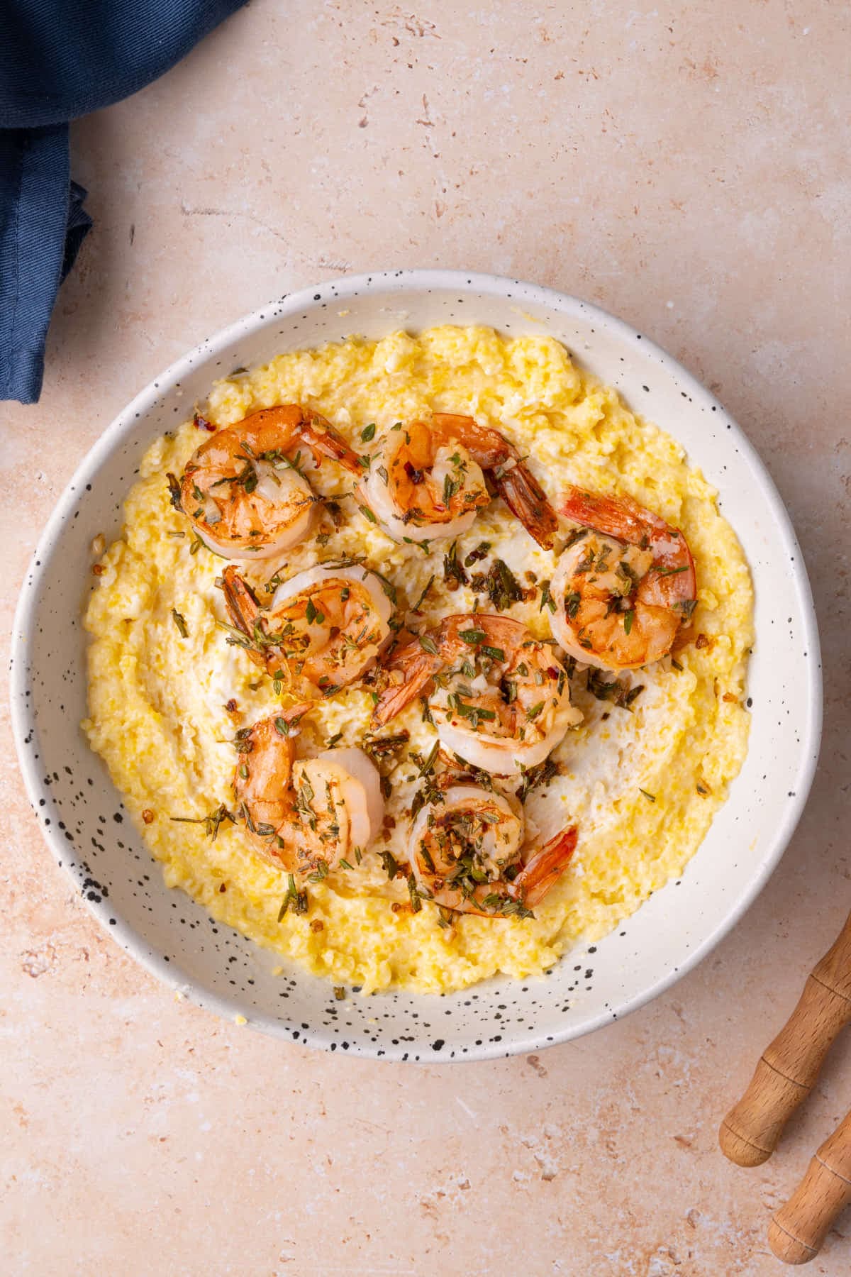 Shallow bowl with a bed of goat cheese polenta topped with herbed shrimp. 