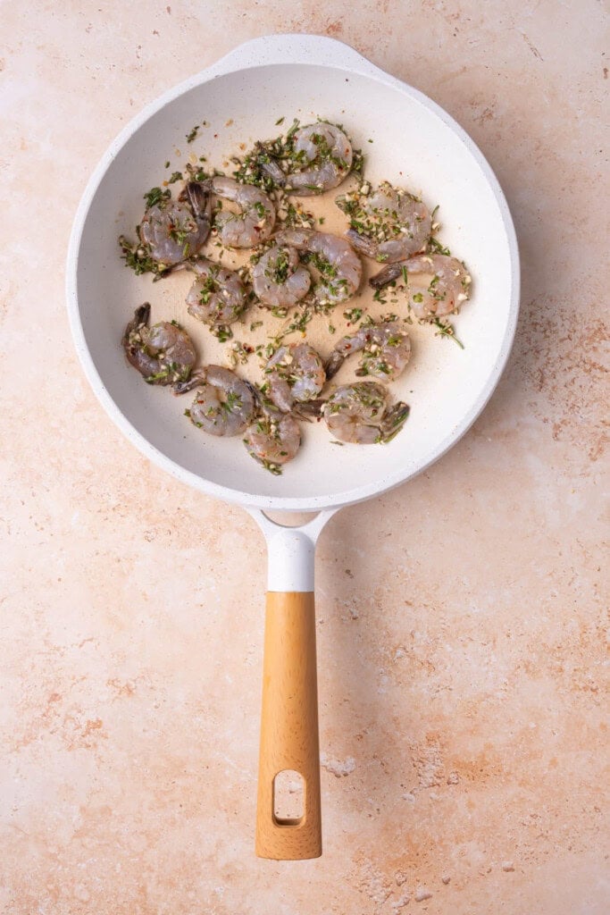 Cooking herb-marinated shrimp in a pan.