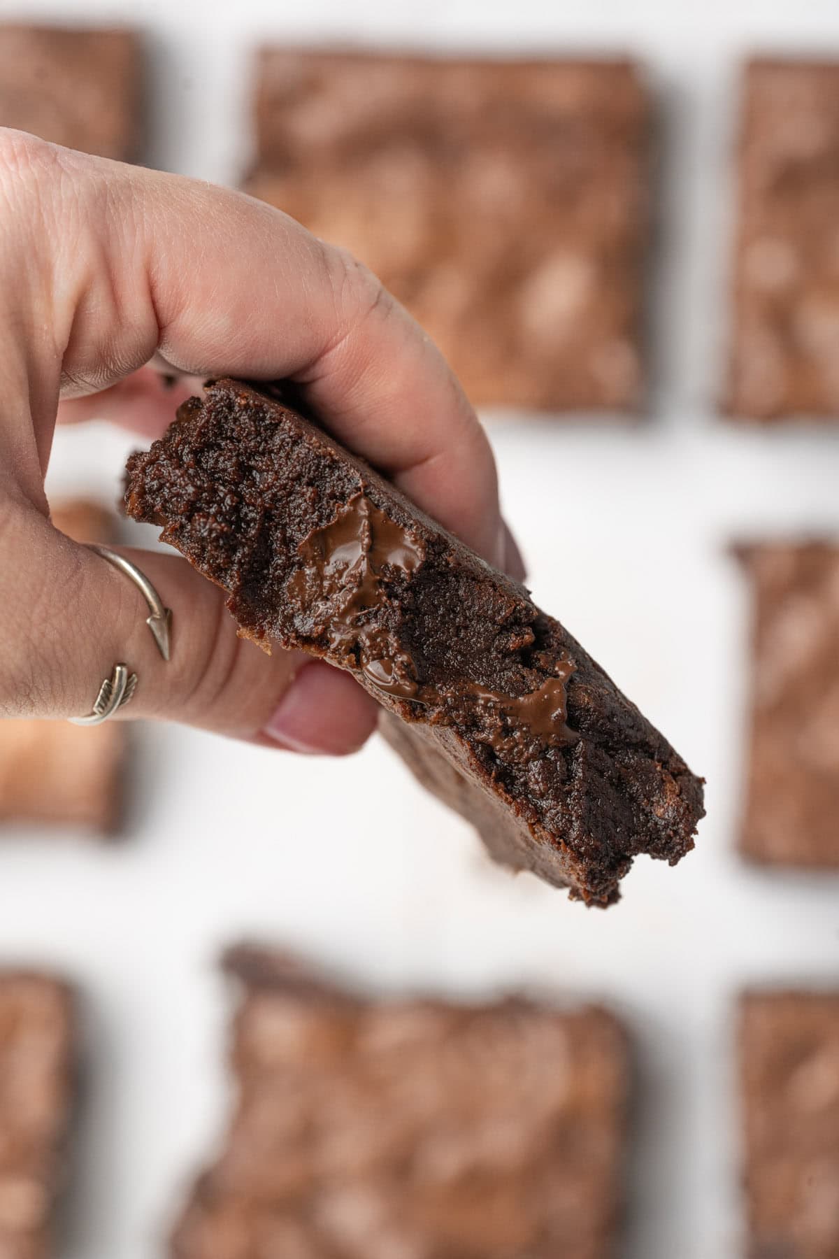 Hand holding a chocolate chip brownie up to the camera.