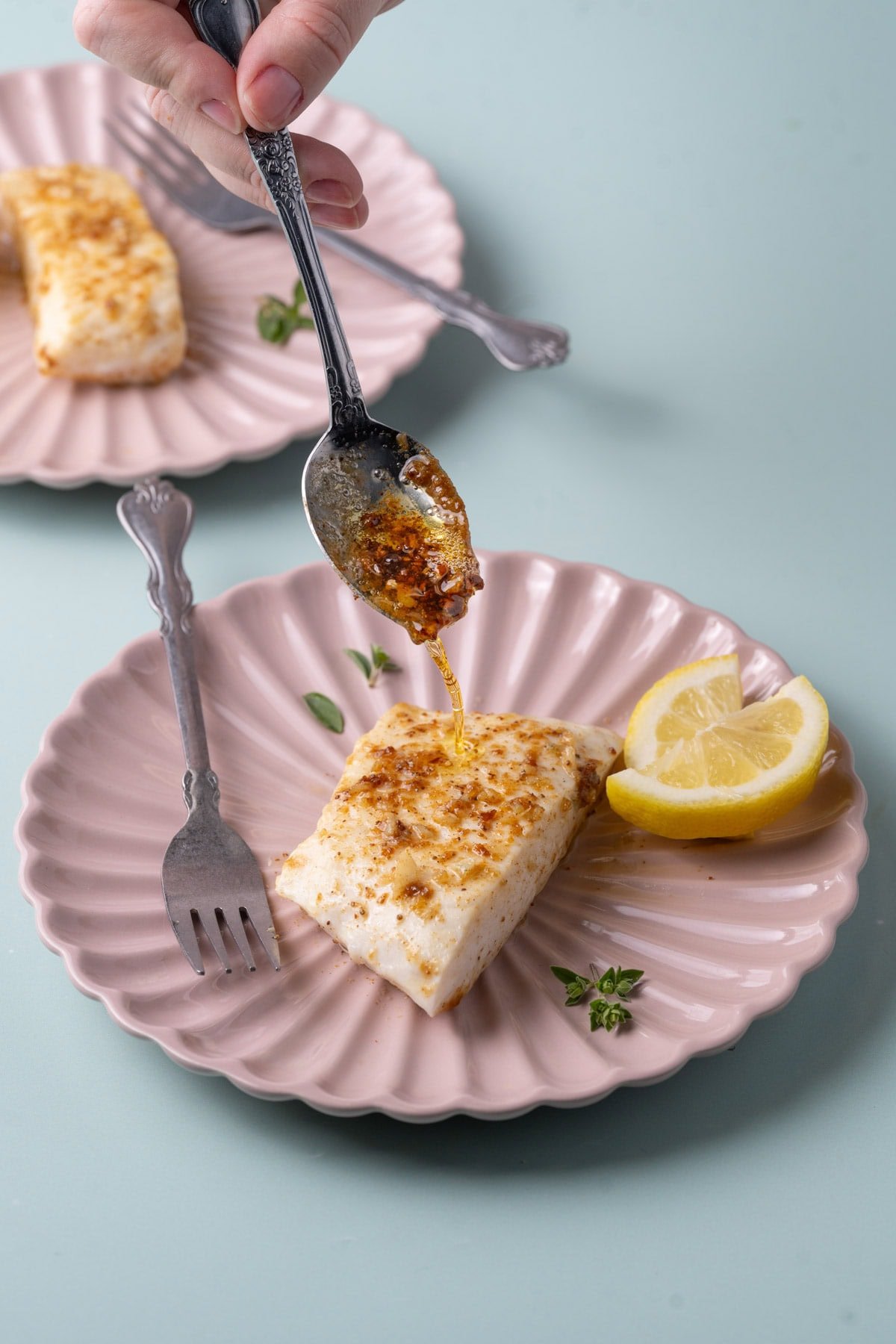 Spooning extra butter sauce over pan-seared halibut.