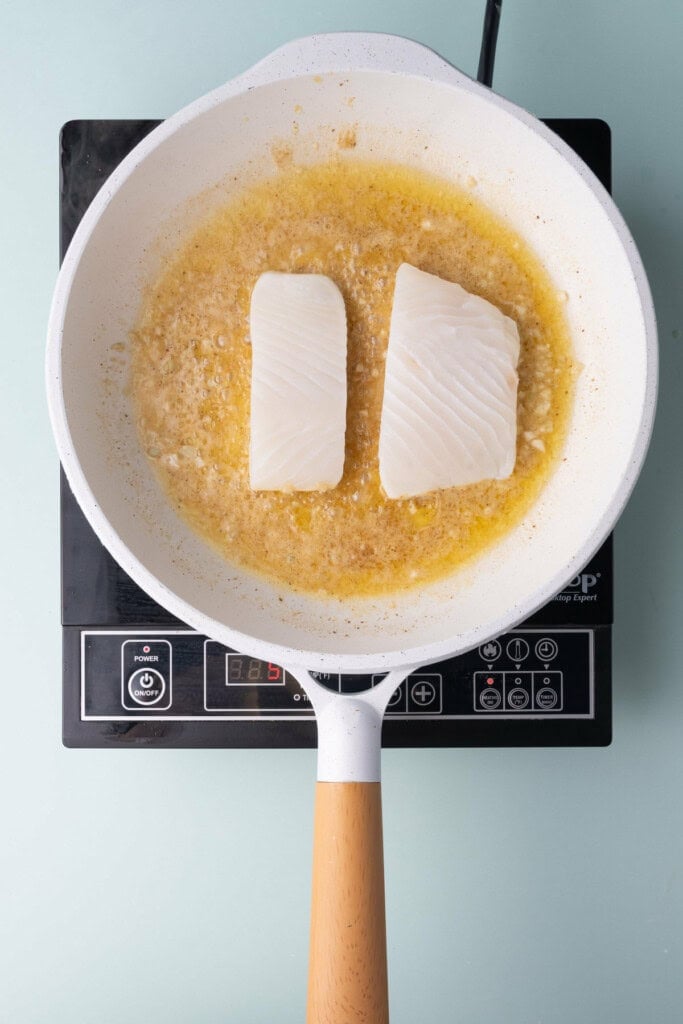 Dropping halibut into pan with hot garlic lemon butter.