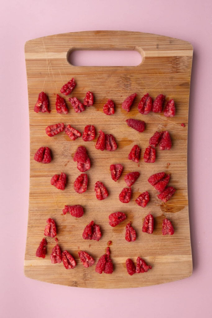 Fresh raspberries on a cutting board sliced in half lengthwise. 