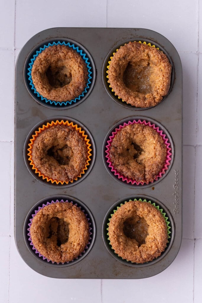 Graham cracker cookie dough baked in a muffin tin after cooling and center sinking to leave a hole.
