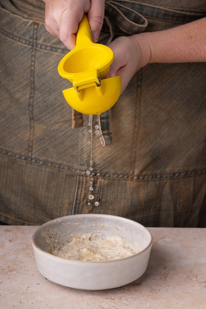 Squeezing fresh lemon juice into breakfast sandiwch sauce.