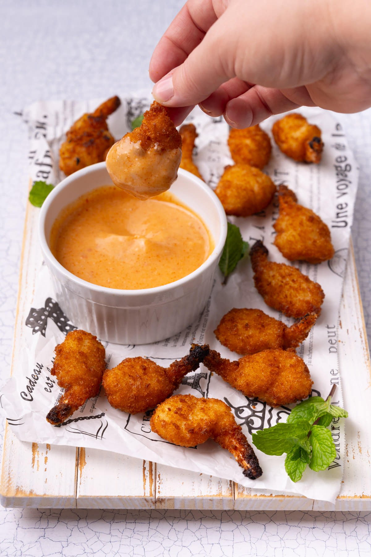 Dipping a piece of fried shrimp into sweet and spicy homemade sauce.