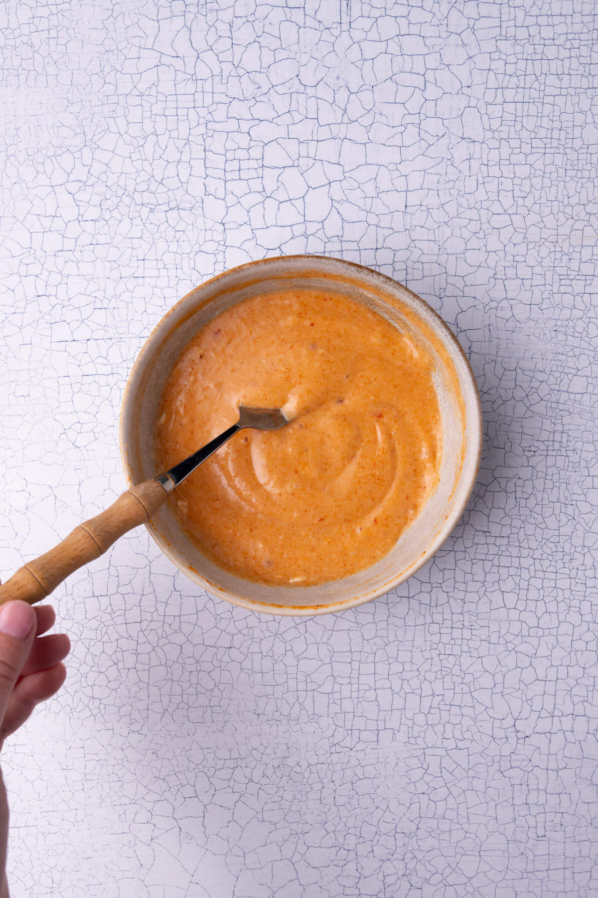 Mixing together mayonnaise, Sweet Thai Chili sauce, and Sriracha in a bowl.