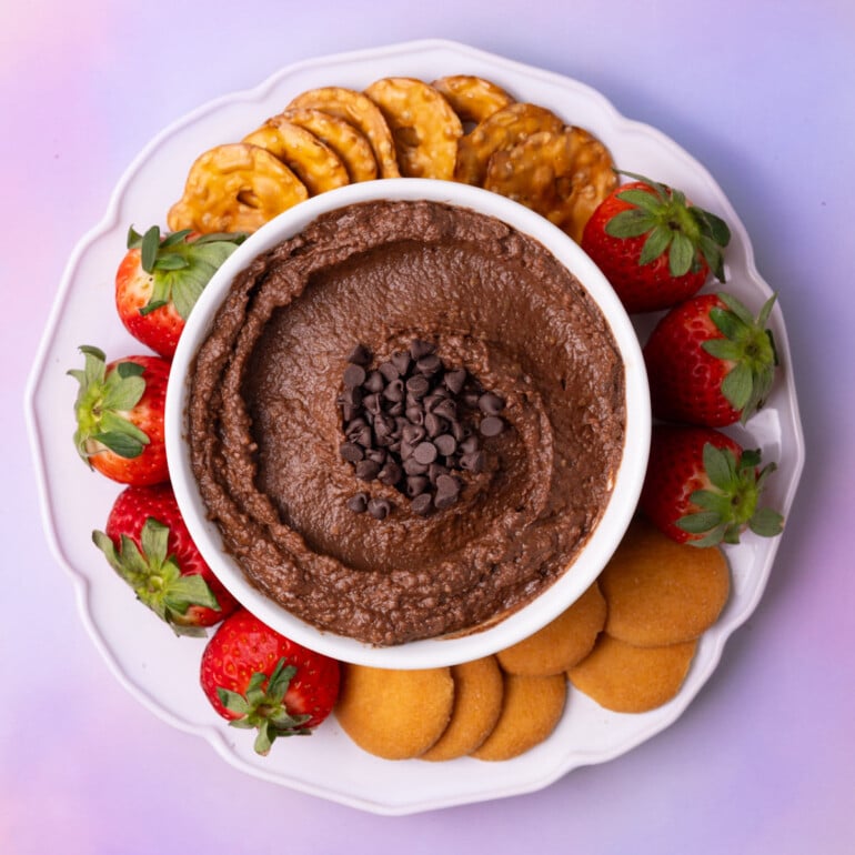Dessert brownie batter hummus topped with mini chocolate chips and surrounded by pretzel crisps, vanilla wafers, and fresh strawberries.