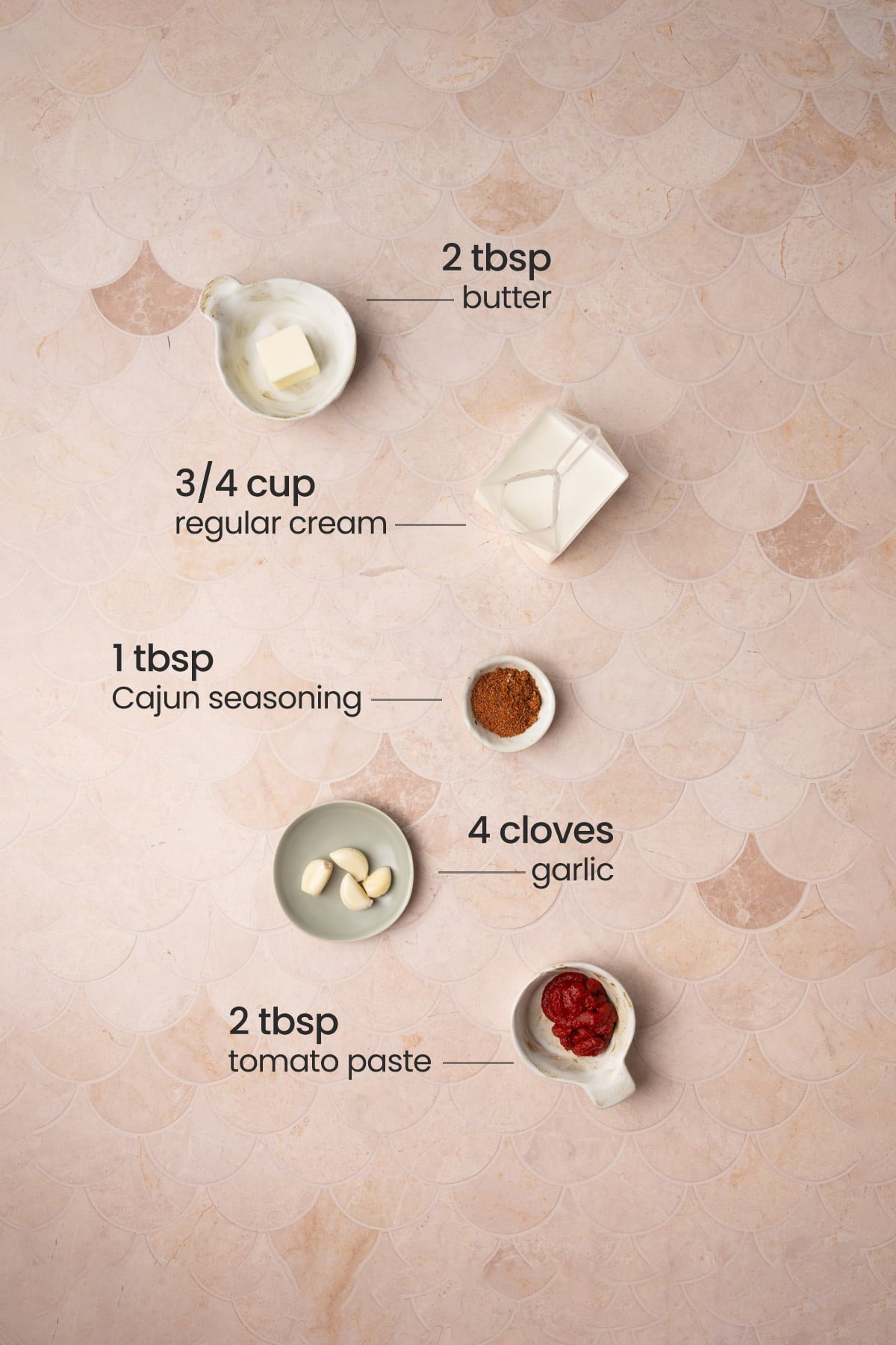 All ingredients needed for Cajun Cream Sauce including butter, cream, Cajun seasoning, garlic, and tomato paste. 