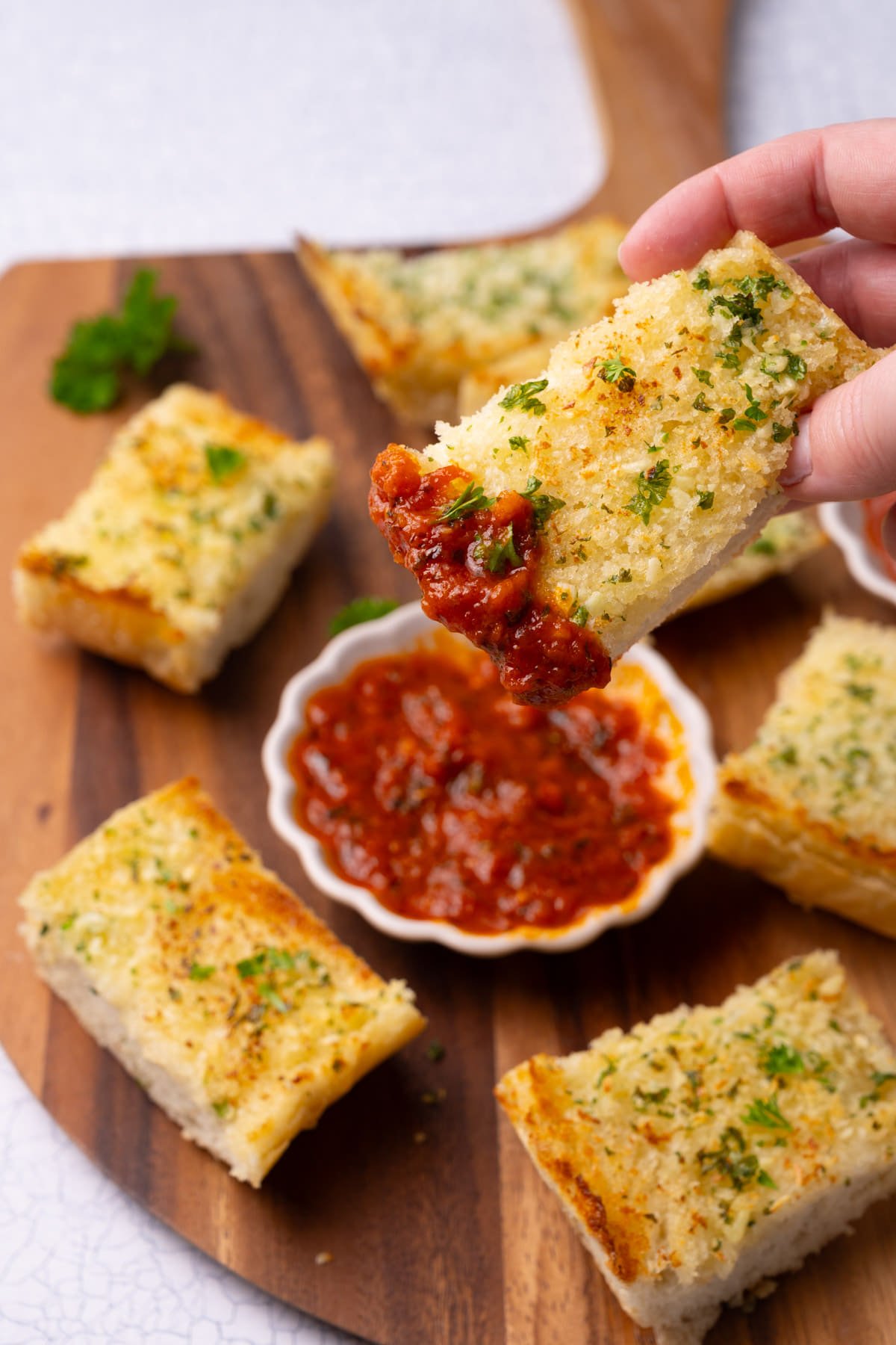 Dipping a piece of garlic bread into marinara sauce.