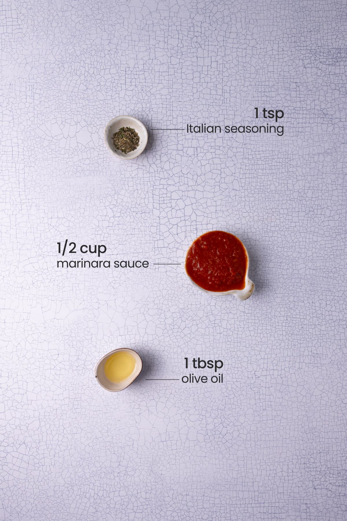 All ingredients needed for marinara dipping sauce including Italian seasoning, olive oil, and marinara sauce. 