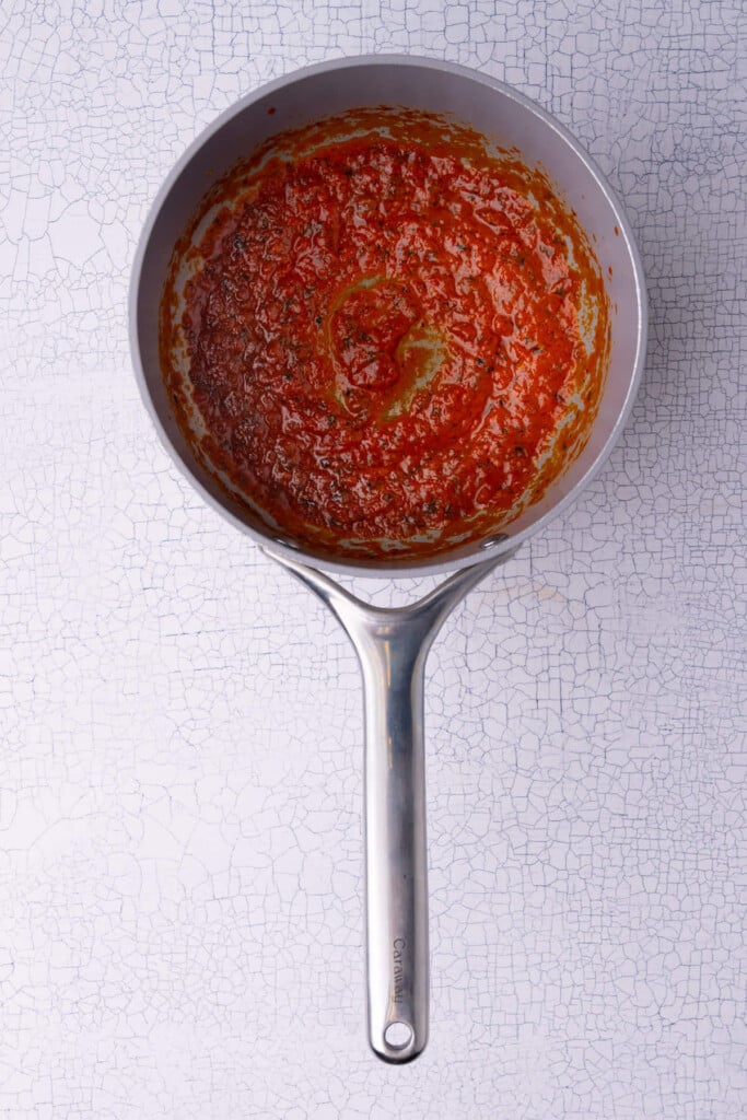 Reducing marinara sauce on the stove with Italian seasoning and olive oil to transform it into a dipping sauce. 