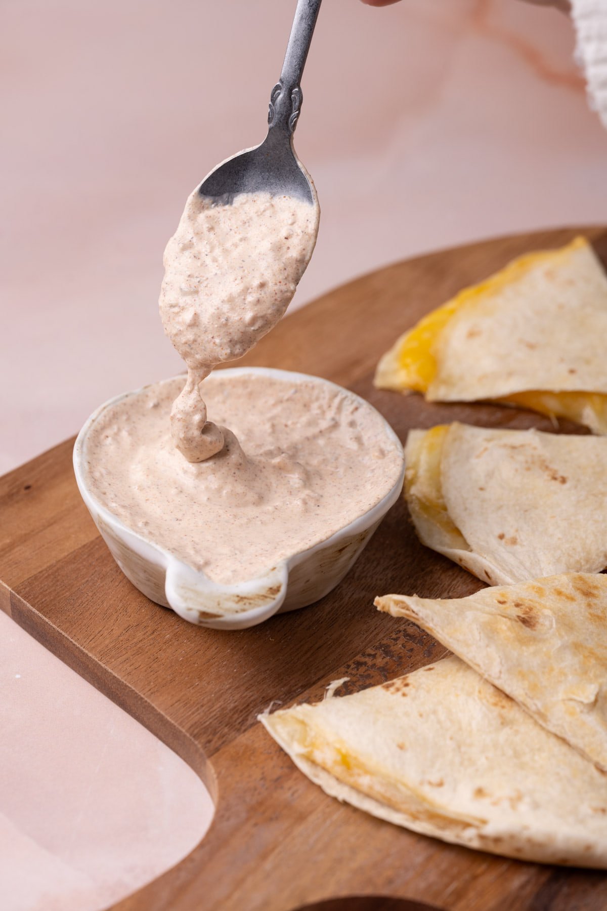 Quesadilla sauce running off a spoon into a bowl of the sauce.