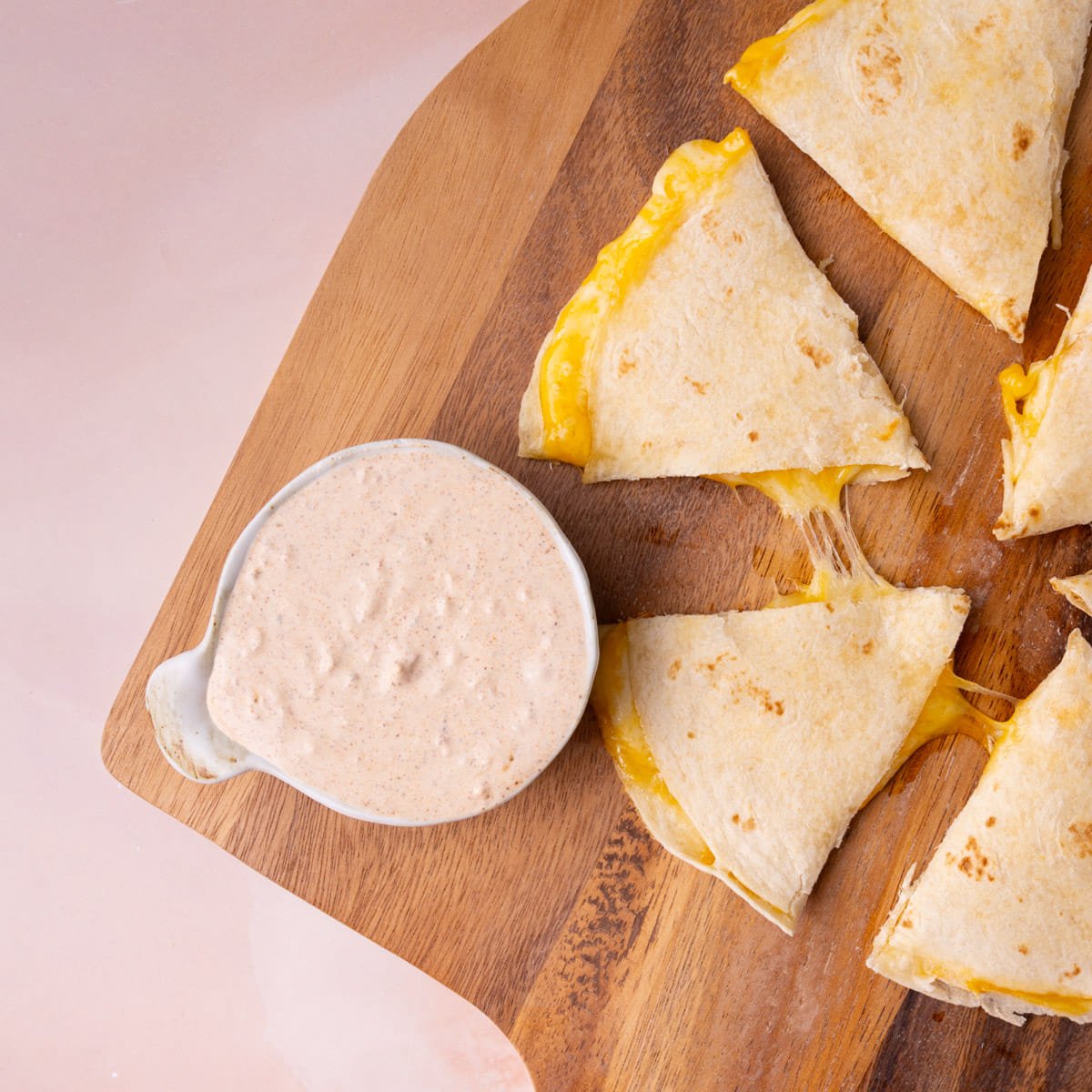Overhead image of a small bowl of sauce next to a cheesy quesadilla.