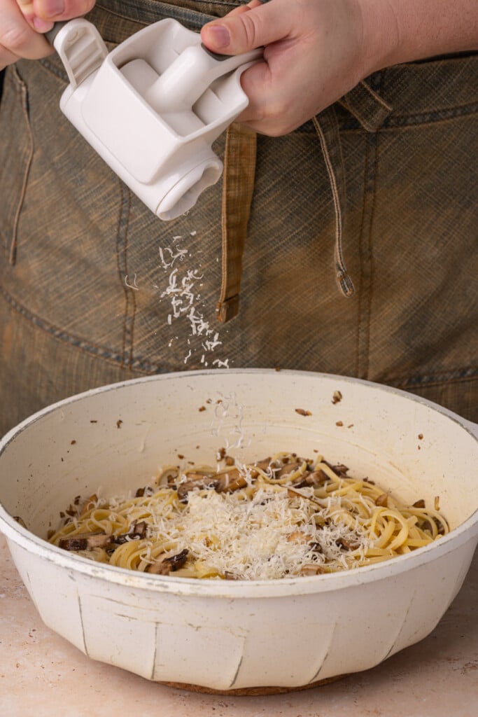 Freshly grating Parmesan over mushroom truffle pasta. 