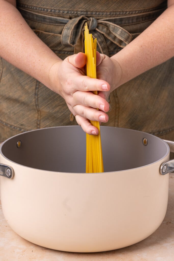 Adding pasta to pot of boiling water to cook al dente. 