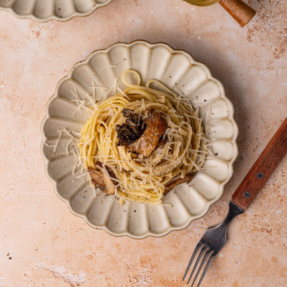 Plate piled high with truffle oil pasta topped with a mushroom medley.