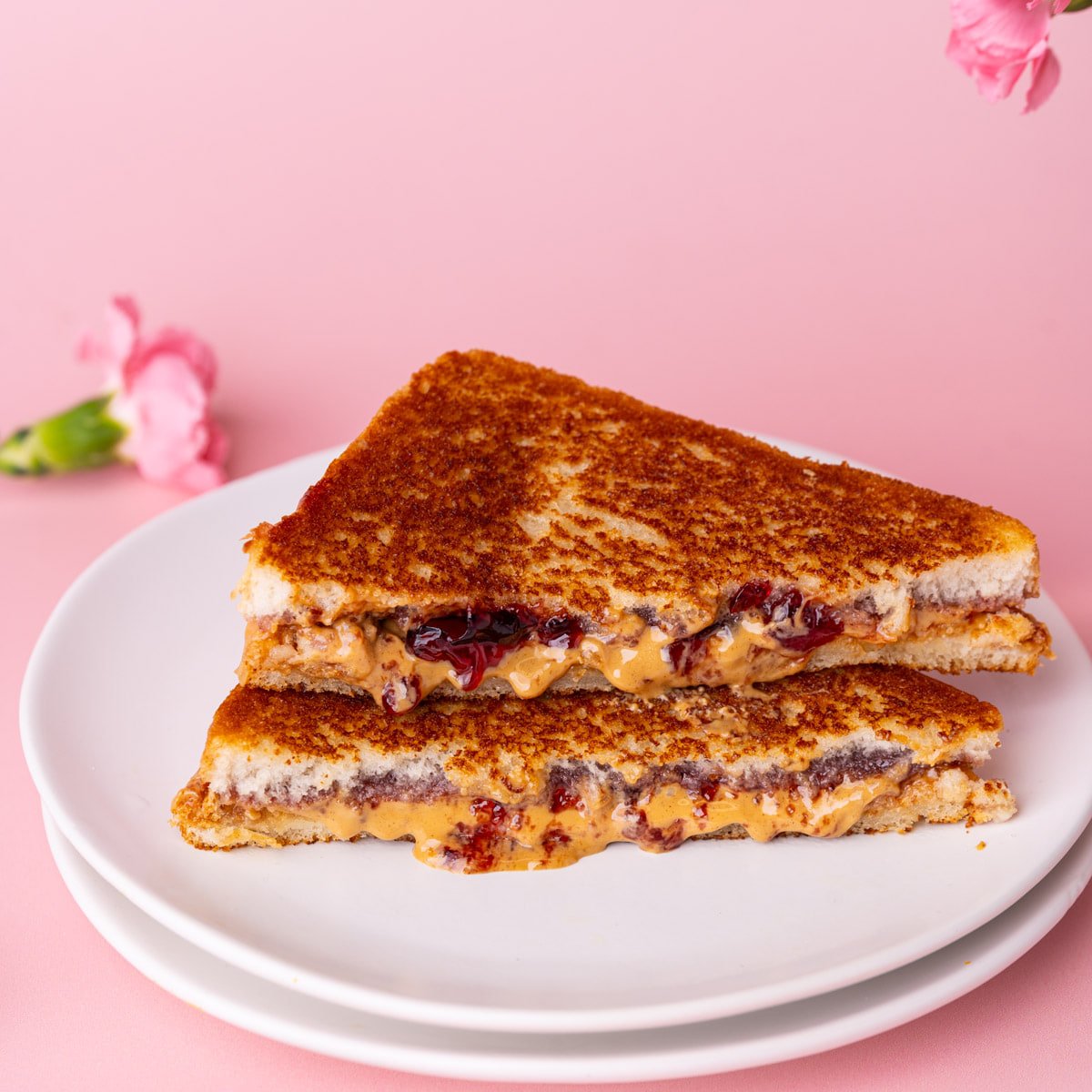 Two halves of a crispy toasted peanut butter and jelly sandwich stacked on top of one another.