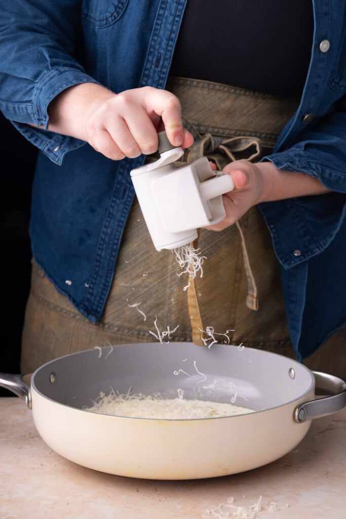 Grating a block of Parmesan into a garlicky sauce. 
