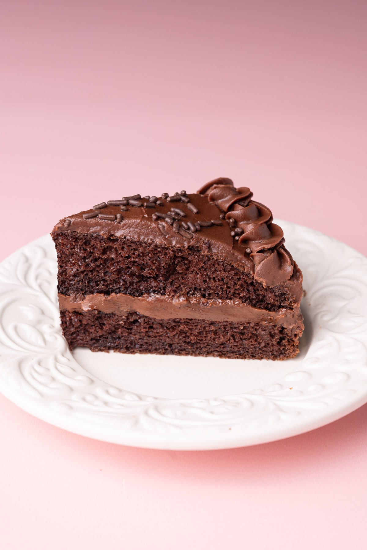Slice of layered chocolate cake with milk chocolate ganache. 