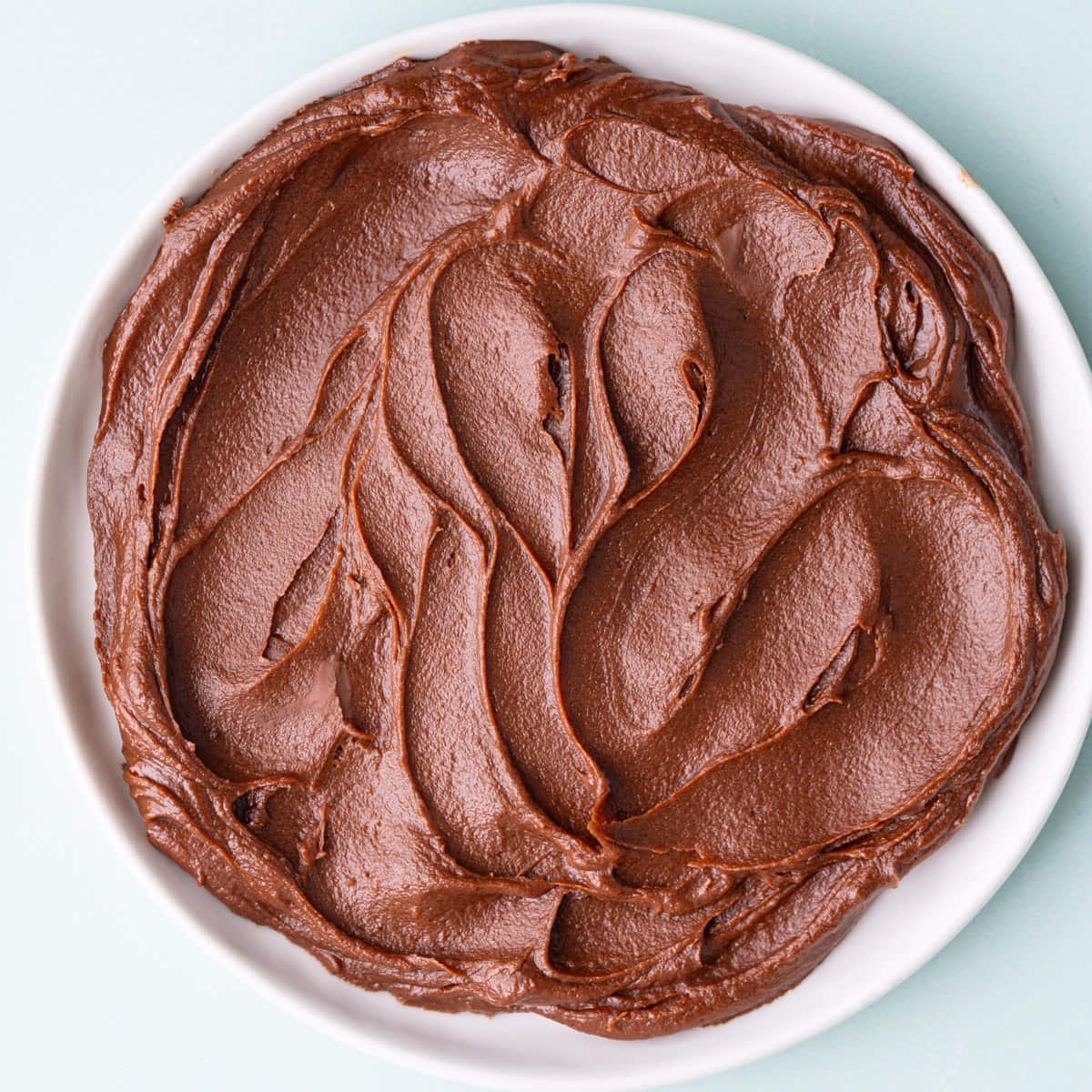 Close up of a small plate with swirls of milk chocolate ganache on it.