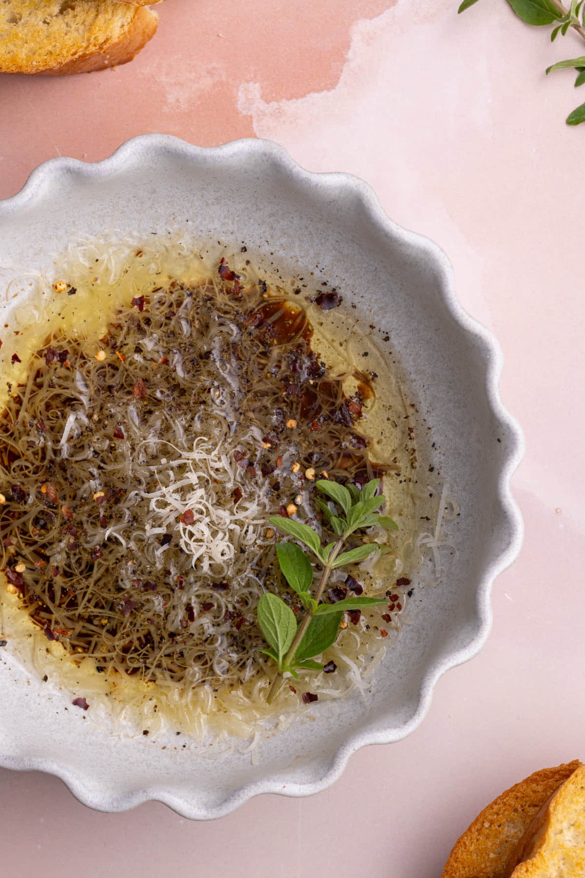 Overhead image of olive oil dipping sauce for bread in a ridged bowl. 