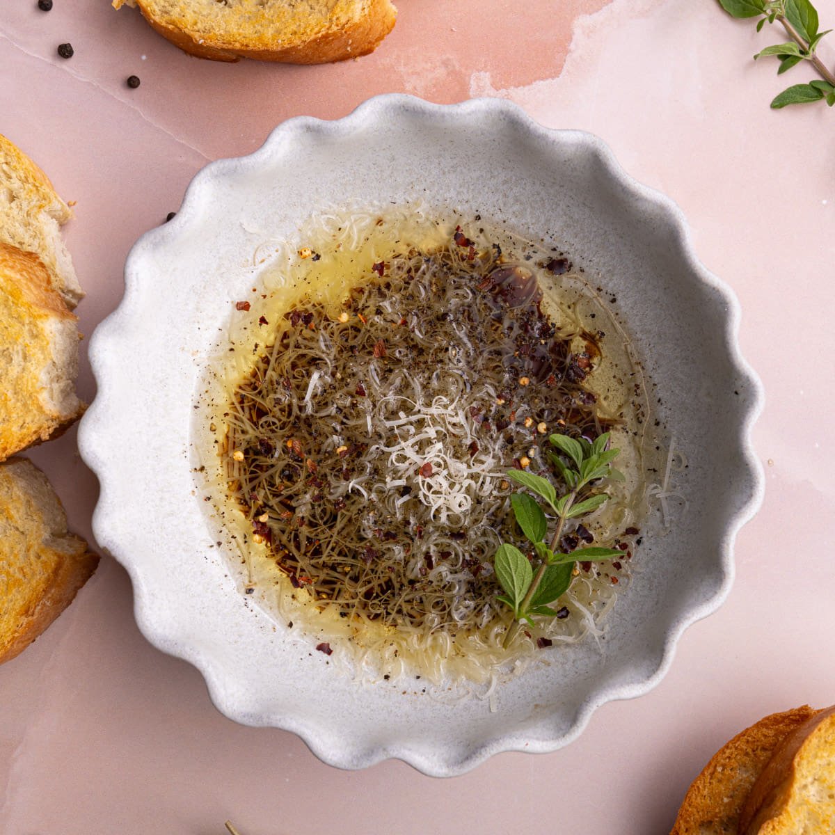 Balsamic vinegar and olive oil dipping sauce for bread in a shallow bowl surrounded by toasted baguette.