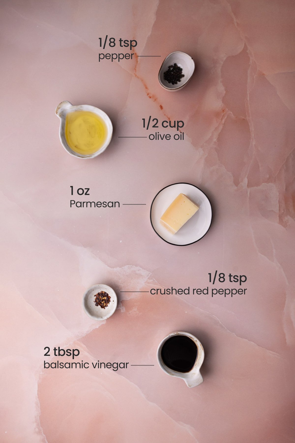 Everything needed for olive oil and balsamic vinegar bread dip including black pepper, extra-virgin olive oil, Parmesan cheese, black pepper, and crushed red pepper flakes. 